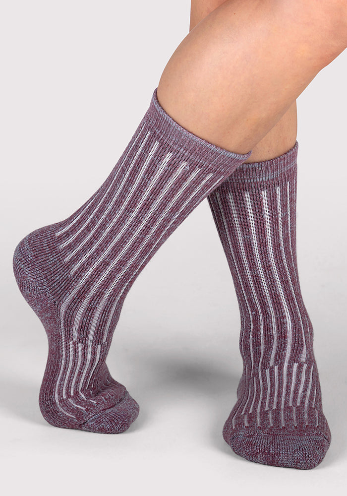 A pair of legs wearing Woolx Womens Joey Crew Socks - Wildflower, featuring a ribbed mauve design with vertical white stripes, posed against a light gray background.