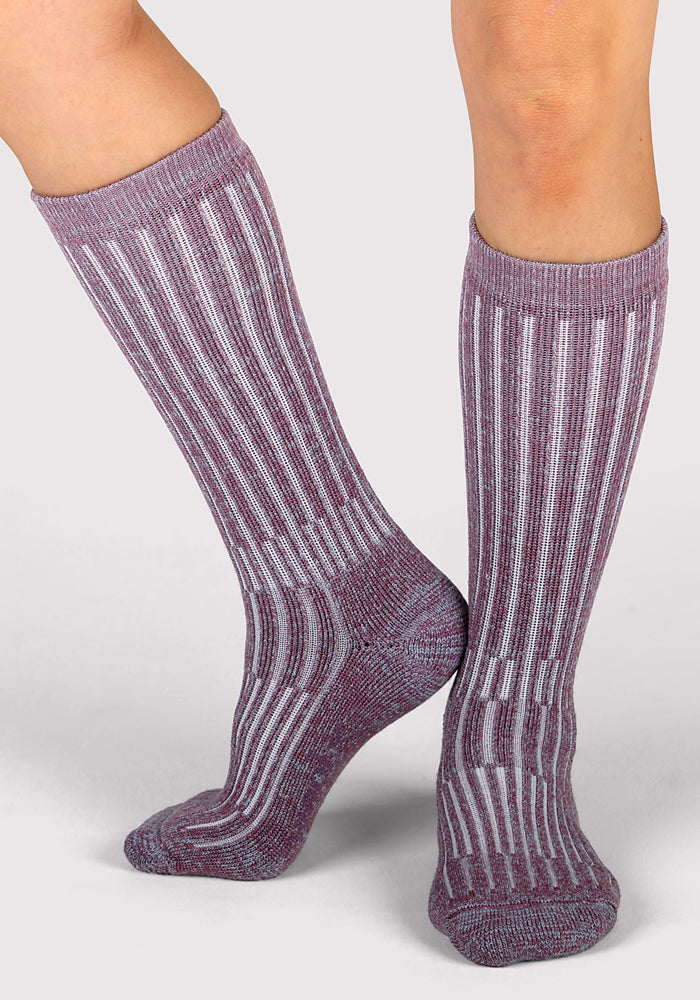 A person wearing Woolx Womens Joey Mid Calf Socks in the Wildflower design stands on a light gray surface, one foot flat and the other slightly raised.