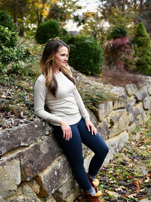Model wearing long sleeve woolx top leaning against stone wall