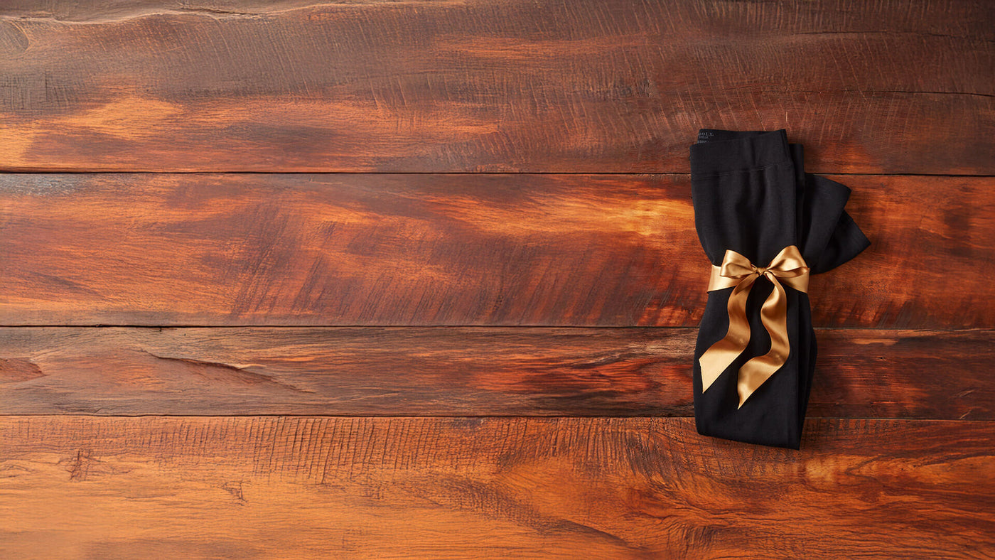 Black leggings sitting on wooden table with golden bow wrapped around it