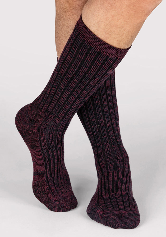 A pair of feet in Woolx Mens Joey Crew Socks - Warm Violet, standing on a light gray surface with one foot slightly crossed in front of the other.