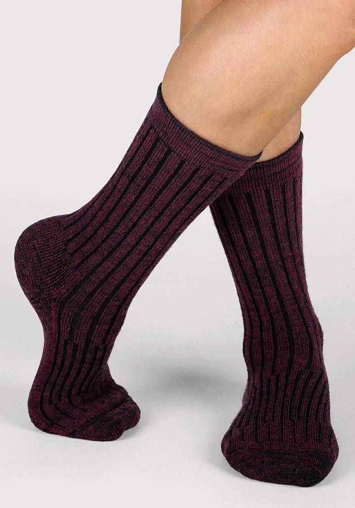 A pair of feet in Woolx Womens Joey Crew Socks - Warm Violet, featuring a maroon and black striped, ribbed mid-calf design. Socks are crossed at the ankles on a plain background, adding cozy comfort to any day.