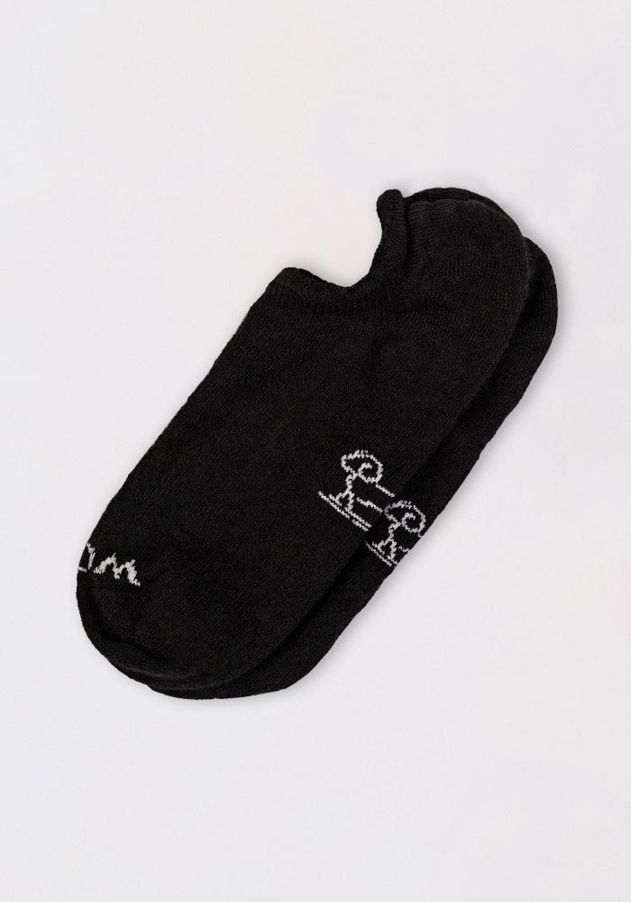 A pair of Woolx Womens Daisy Ped Socks in black Merino wool, featuring a small white daisy graphic and text near the toe, shown on a plain light background.