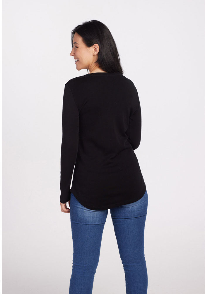 Woman with dark hair in Woolx’s Eva Petite Tunic - Black and blue jeans, smiling and seen from behind.
