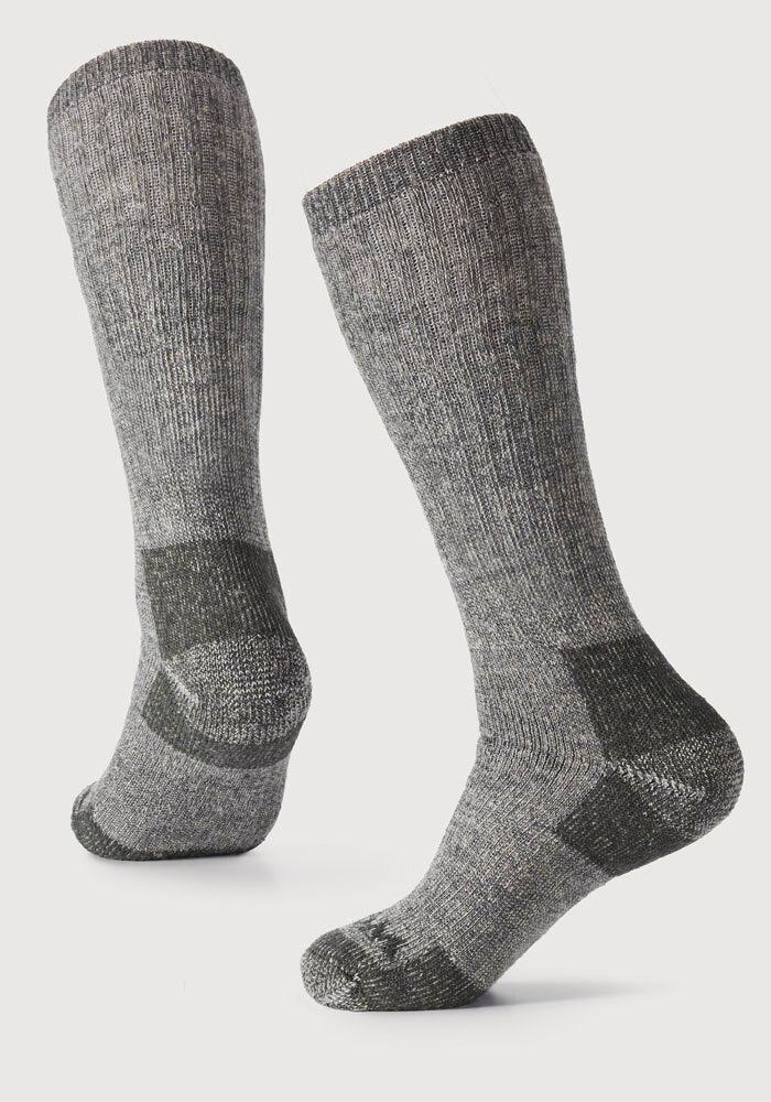 A pair of Woolx Womens Extreme Over The Calf Socks in Forest Dark Moss, featuring heavyweight merino wool with darker reinforced heels, toes, and soles, displayed on a plain white background.