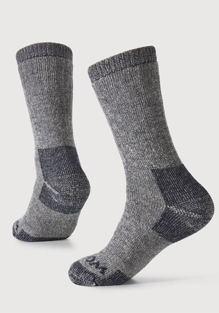 Experience ultimate comfort in Woolx Womens Extreme Crew Socks in Charcoal Heather, featuring thick, mid-calf warmth with contrasting dark heels, toes, and arch accents—perfect for cold weather. Displayed standing against a plain white background.