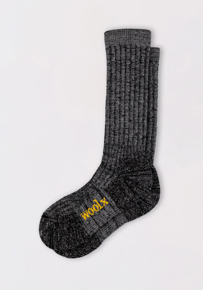 The Woolx Mens Joey Mid Calf Socks in dark navy marled are thick, ribbed Merino wool hiking socks with "wool" stitched in yellow on the sole, designed for mid-calf fit and shown against a plain white background.