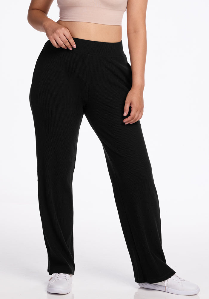 Model wears Woolx Luca Petite Pants in black, a beige crop top, and white sneakers against a white backdrop.