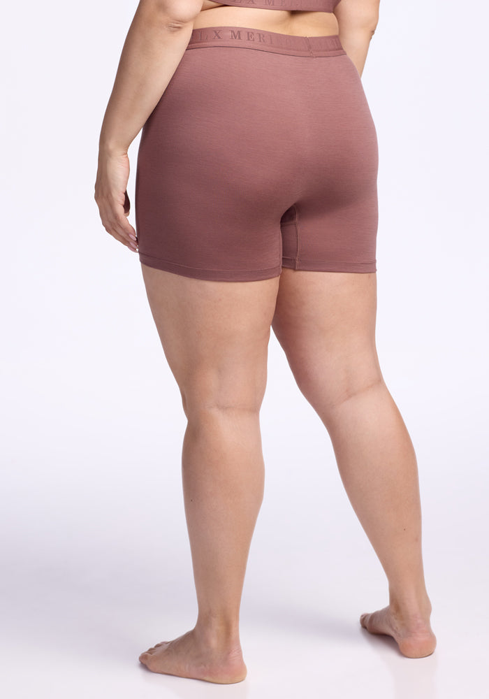 A person stands barefoot on a white background, shown from the back, wearing Woolx Elliott Boyshort in Nutmeg, a high-waisted merino wool boyshort.
