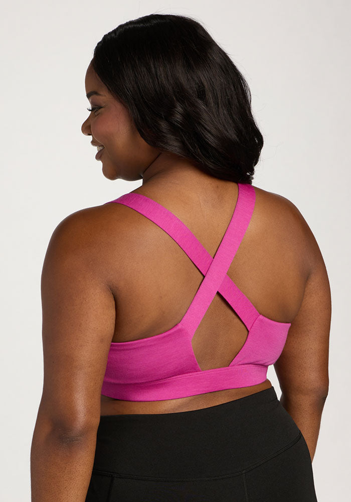 Woman wearing the Woolx Livi Bra in Summer Sorbet with crisscross back straps and black leggings.