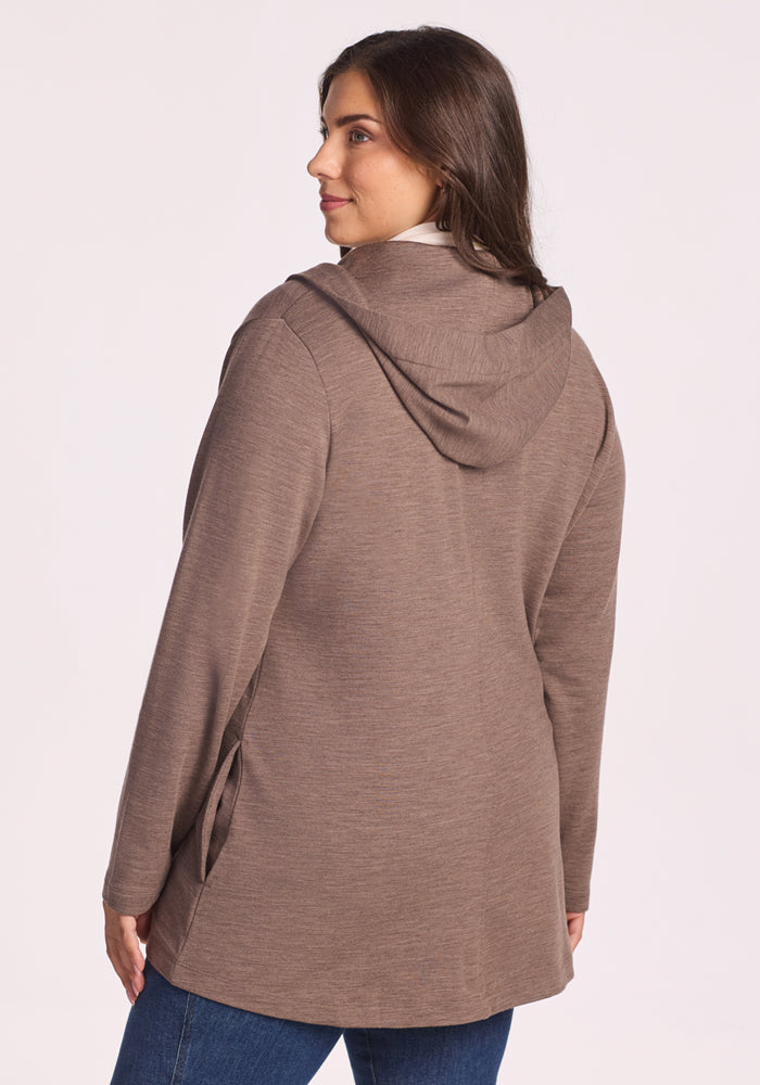 A woman with long brown hair is seen from the back wearing the Woolx Edna Hooded Cardigan in Simply Taupe and blue jeans, standing against a light background.