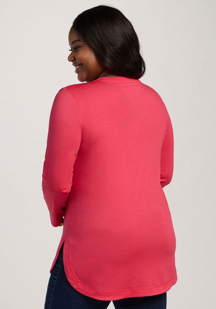 Woman smiling, facing away, in the Woolx Hazel Tunic - Berry Ice Pop and dark jeans against a light background.