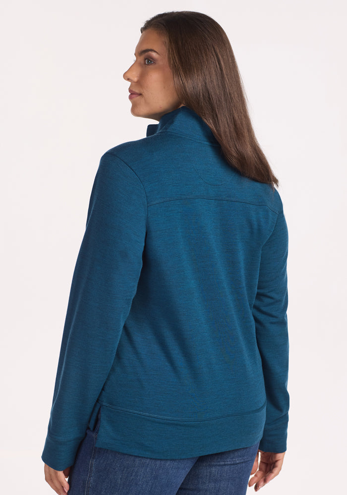 A woman with straight brown hair is shown from the back, wearing the Woolx Annie 3 Button Pullover in Majolica Blue and blue jeans, standing against a plain light background.