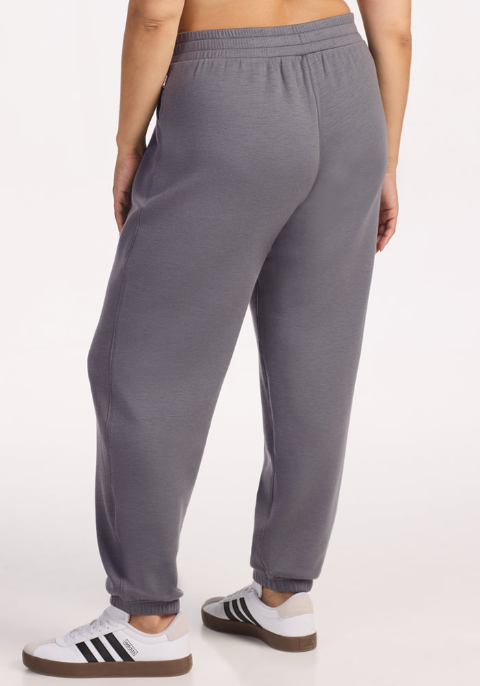 A person wearing Woolx Parker Sweatpants in Arctic Dusk stands on a light background, shown from the waist down and facing away from the camera.