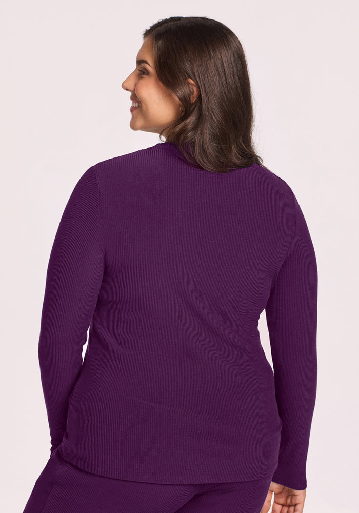 A woman with long brown hair, seen from behind, wears the Woolx Hadley Ribbed Crew in Majestic Purple against a plain light background.