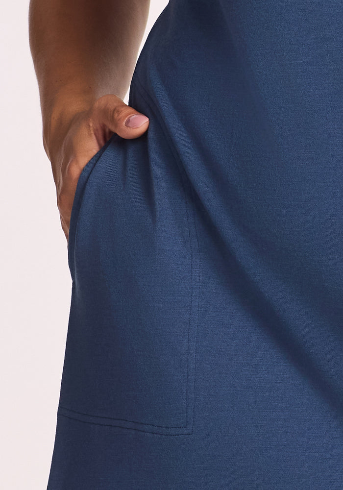 A close-up shows a hand in the pocket of the Woolx Cassie Dress in Starry Night blue, set against a plain light background.