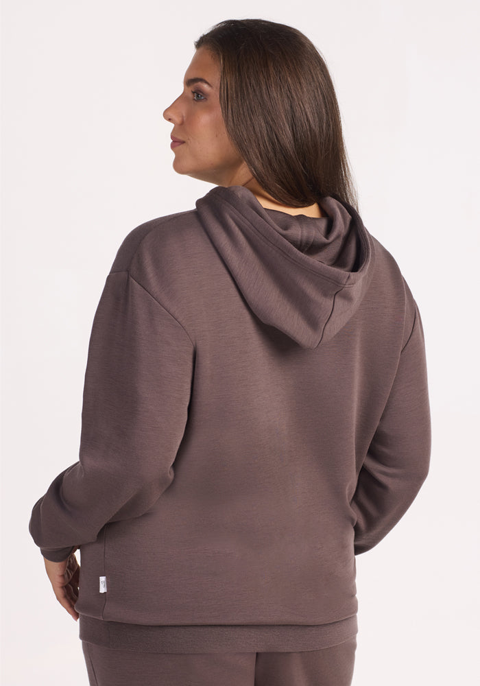 A woman with long brown hair is shown from the back, wearing the Woolx Avery Hoodie in Plum Truffle and matching pants, against a plain white background.