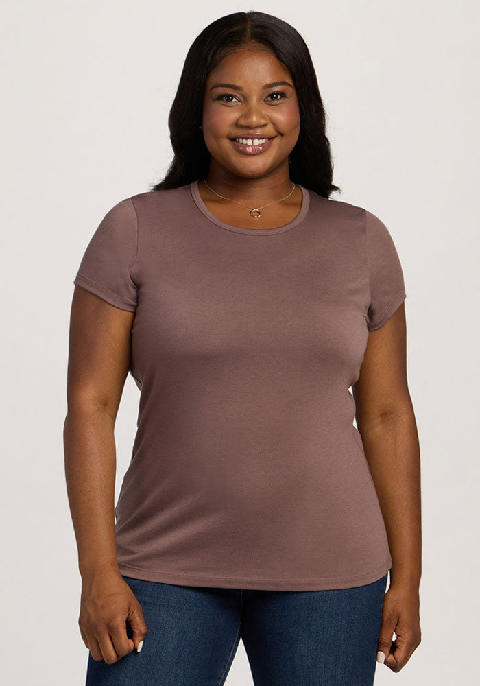 A woman in a Woolx Addie Crew Neck - Peppercorn shirt and jeans smiles at the camera against a plain background. 
