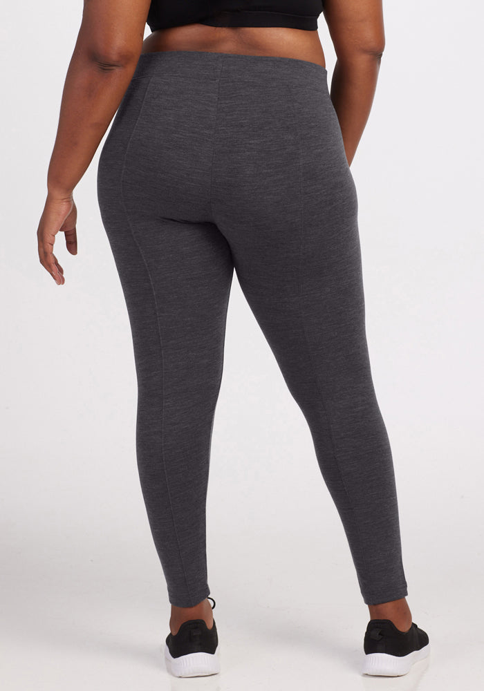 A person models Woolx Stella Leggings in Cinder Melange, paired with black sneakers, standing with their back to the camera against a plain white background.