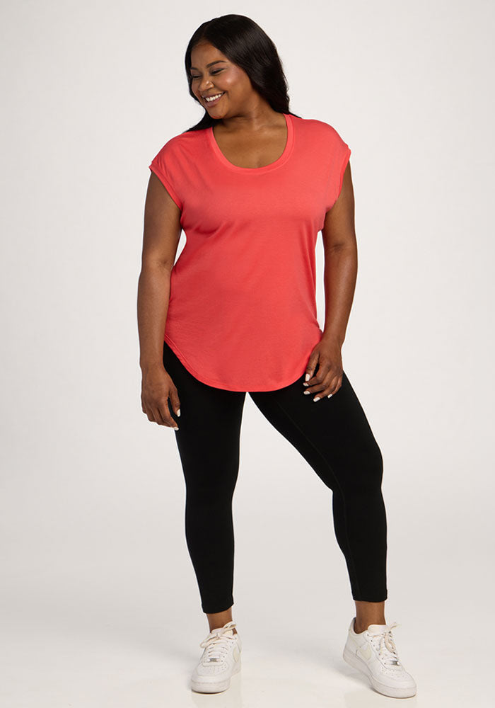 Woman in the Woolx Gabi Tunic Top - Hibiscus, black leggings, and white sneakers smiles against a plain background.