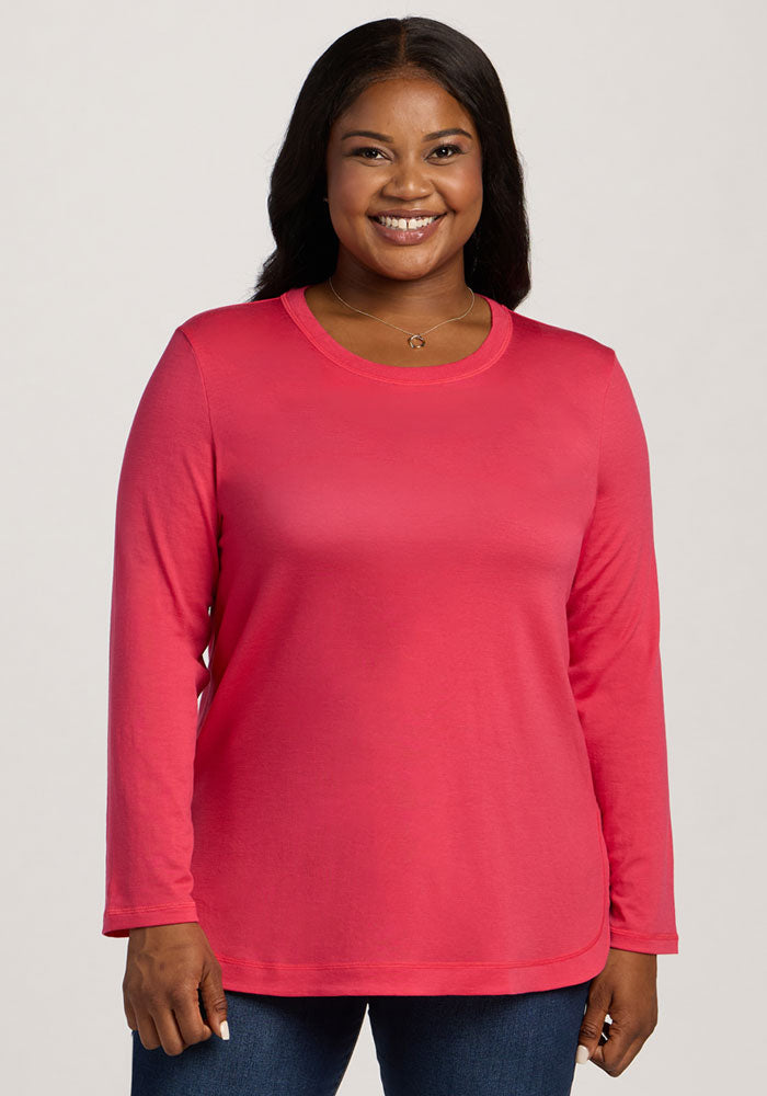 Smiling woman in Woolx Hazel Tunic - Berry Ice Pop and blue jeans, standing against a light background. 