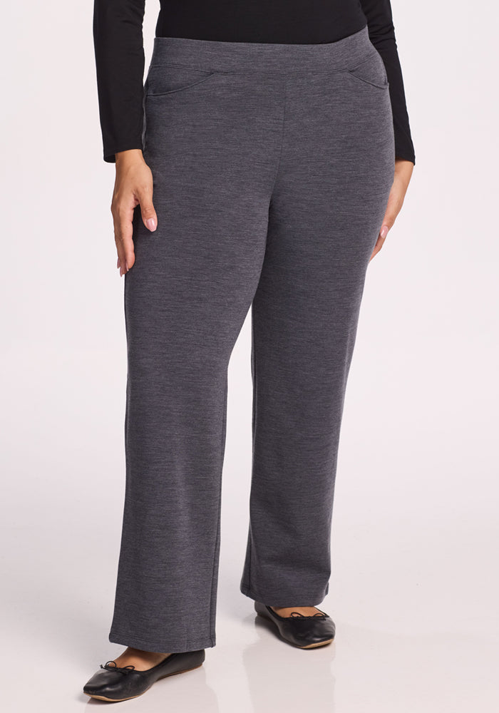 A person wears Woolx Ellie Wide Leg Pants in Cinder Melange, styled with black flats, standing against a plain background. Their arms rest naturally by their sides, and only the lower body is visible. 