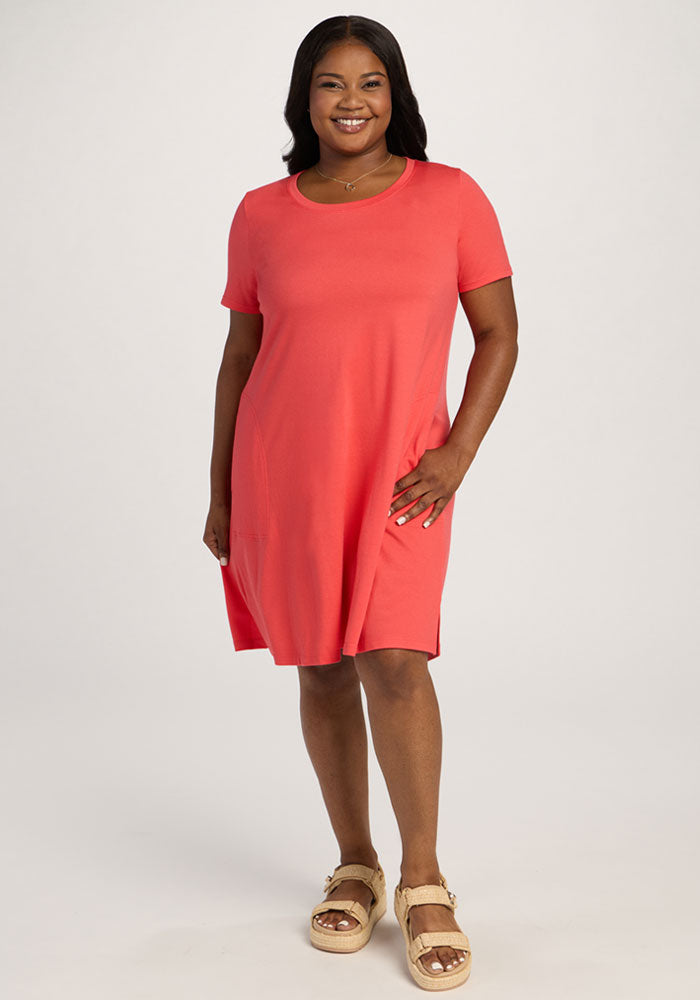 Smiling woman in the Woolx Georgie Dress - Hibiscus and sandals stands against a plain light background. 