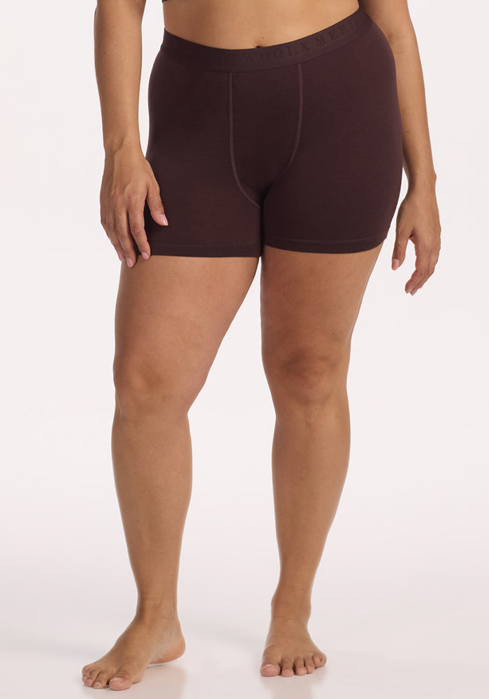 A person stands barefoot in Woolx Elliott Boyshort - Chocolate Plum, temperature-regulating underwear with an elastic waistband, against a plain white background. Their arms are relaxed by their sides. 