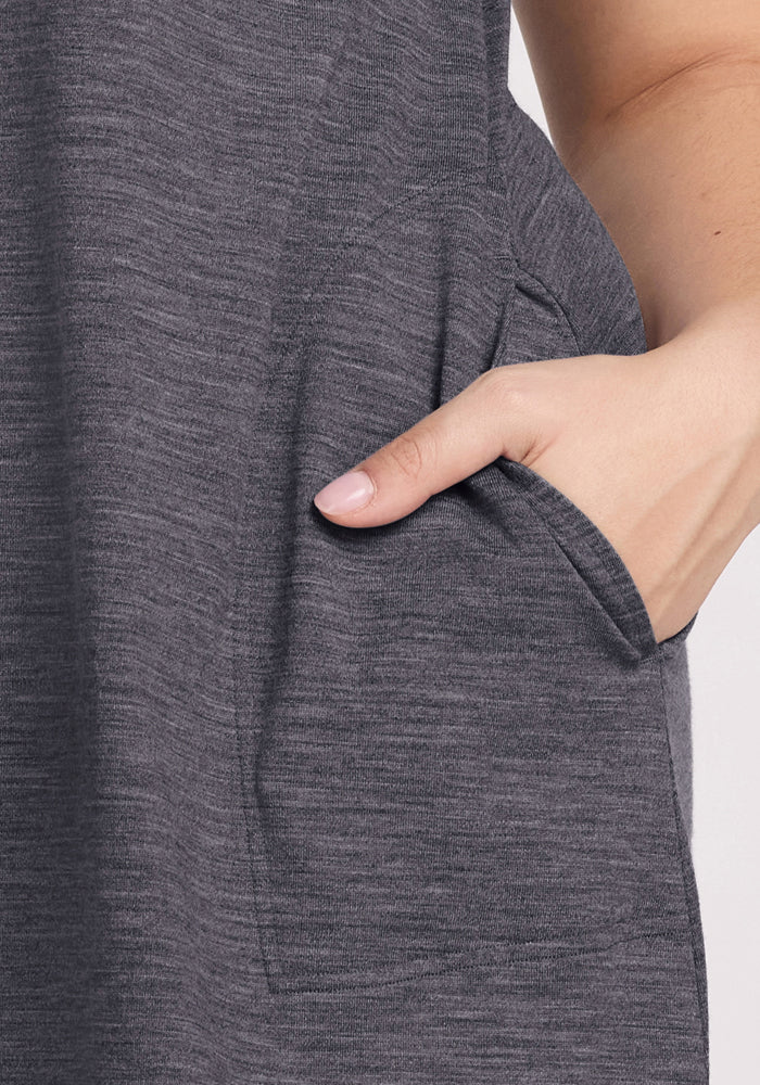 A close-up shows a hand resting in the pocket of the Woolx Clara Dress - Cinder Melange, with part of the arm and side visible, highlighting the comfort and style of this textured Merino wool summer dress.