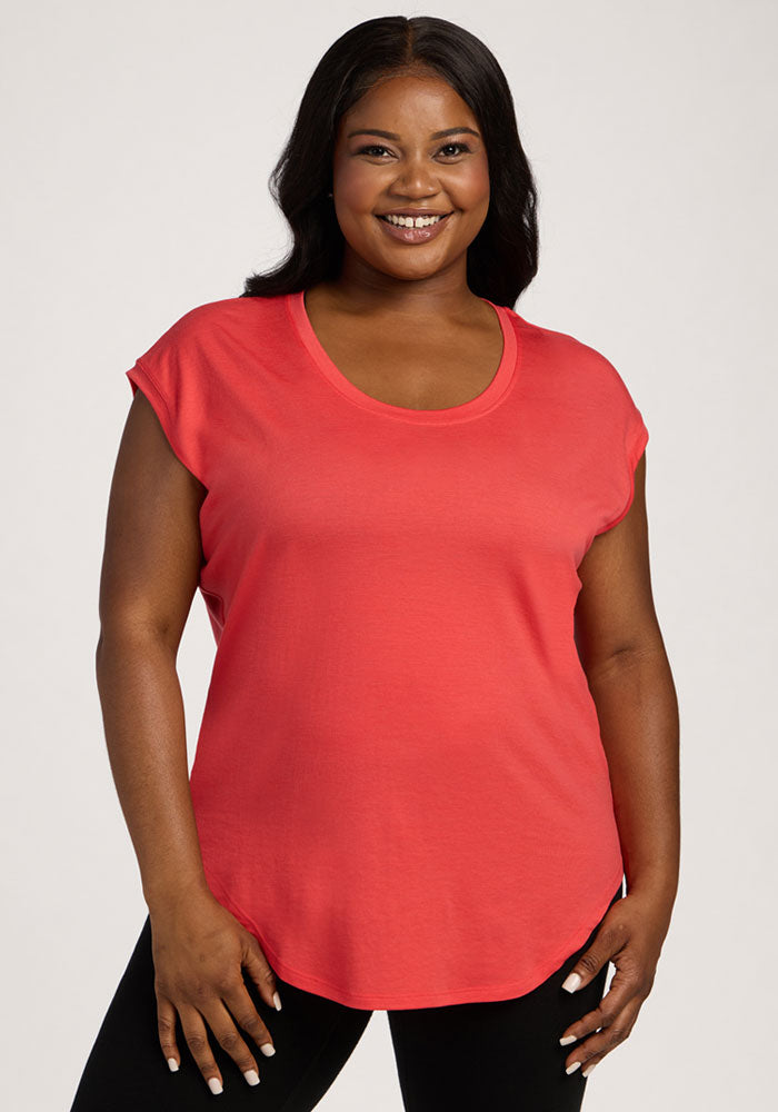 Smiling woman wears Woolx Gabi Tunic Top in Hibiscus with black pants, standing against a plain light background. 