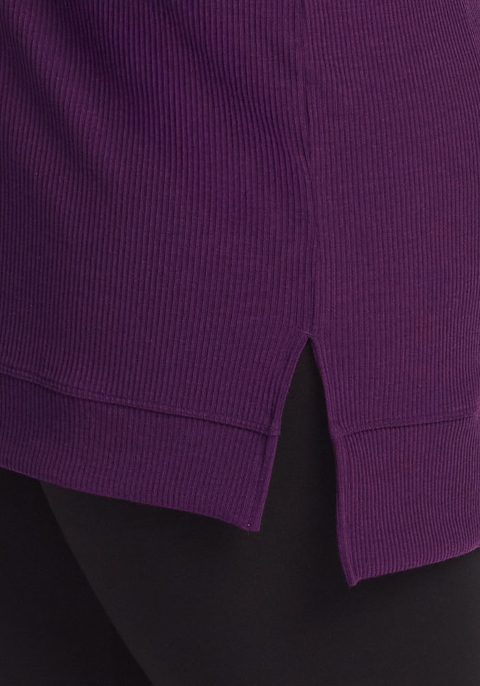 Close-up of the Woolx Evie Ribbed Tunic in Majestic Purple, featuring a cozy ribbed fabric and a small side slit at the hem, styled over black pants.