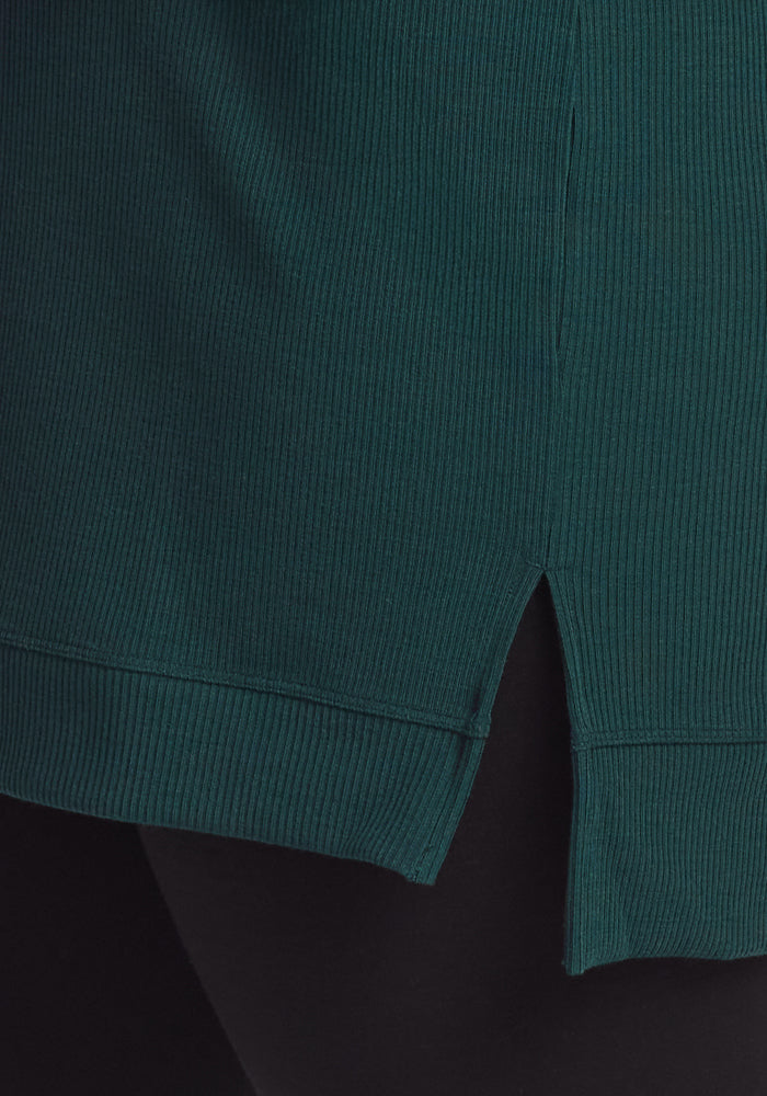 Close-up of the Woolx Evie Ribbed Tunic in Deep Timber, a cozy women's top with ribbed knit, featuring a small side slit at the hem that reveals black fabric underneath.