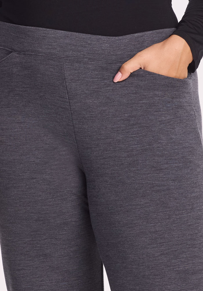 A person wearing Woolx Ellie Wide Leg Pants in Cinder Melange and a black top, with their right hand in the pants pocket.