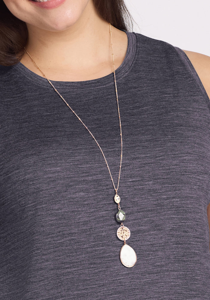 A woman wears the Woolx Clara Dress in Cinder Melange, a sleeveless, breathable summer dress, paired with a long gold necklace featuring multiple pendants. Only the lower half of her face is visible.