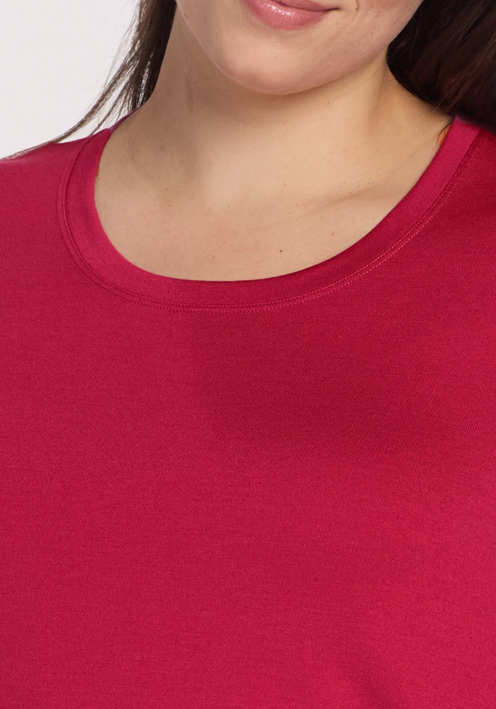 A close-up of a person wearing Woolx’s Rissa A Line Dress in Poppy Spark, featuring a round neck and subtle smile—ideal for fall winter layering or pairing with other cozy Merino wool pieces.