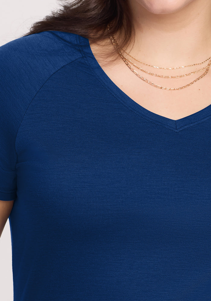 A close-up of a person wearing the Woolx Mia V Neck in Estate Blue paired with a layered gold necklace, with their face partially out of frame.