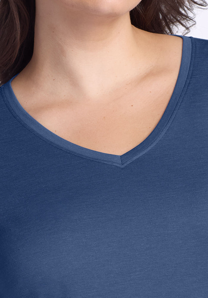 A close-up shows someone wearing the Woolx Millie Long Sleeve in Starry Night, highlighting the neckline and upper chest. The moisture-wicking merino wool fabric ensures all-day comfort. Hair is visible on one side; face is partially out of frame.