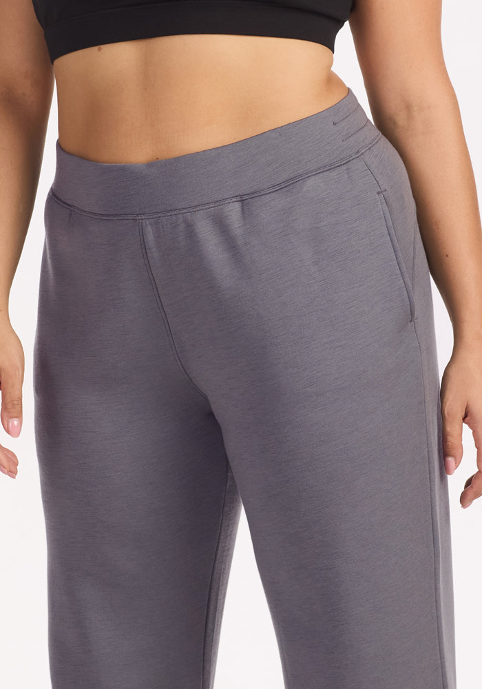 A close-up of a person wearing Woolx Bree Lounge Pants in Arctic Dusk, featuring a high-waisted, relaxed fit paired with a black crop top, arms at their sides against a plain background.