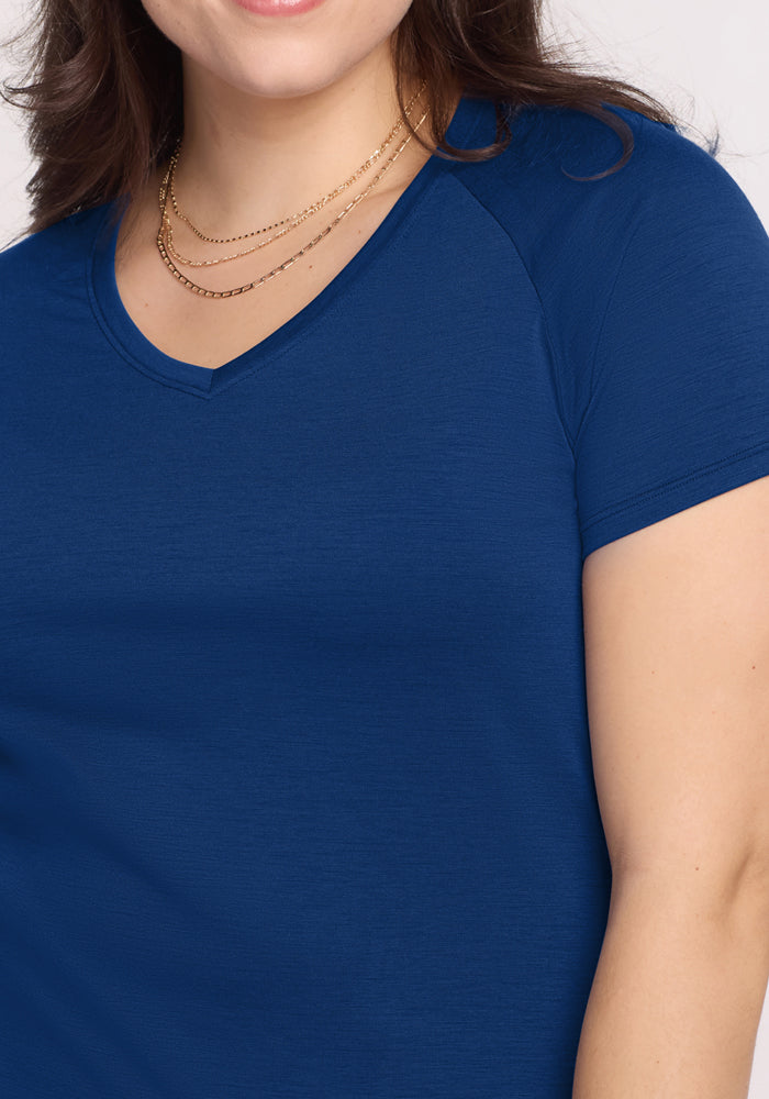 A woman wears the Woolx Mia V Neck in Estate Blue, a wrinkle-resistant short sleeve shirt, styled with layered gold necklaces and shown from shoulders to upper torso against a light background.