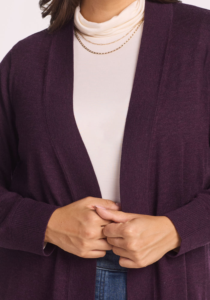 Close-up of a person wearing the Woolx Macie Sweater in Deep Plum over a white turtleneck, accessorized with a thin gold chain necklace and clasping their hands in front.