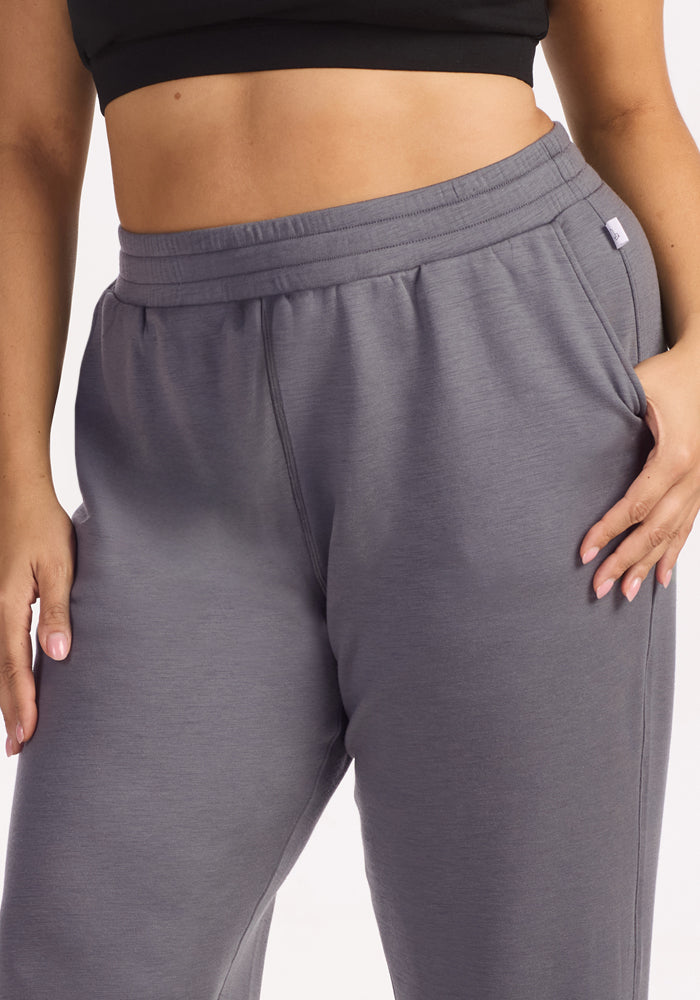 A person models the Woolx Parker Sweatpants in Arctic Dusk, standing with one hand on their hip and the other by their side, highlighting the waist and upper legs.