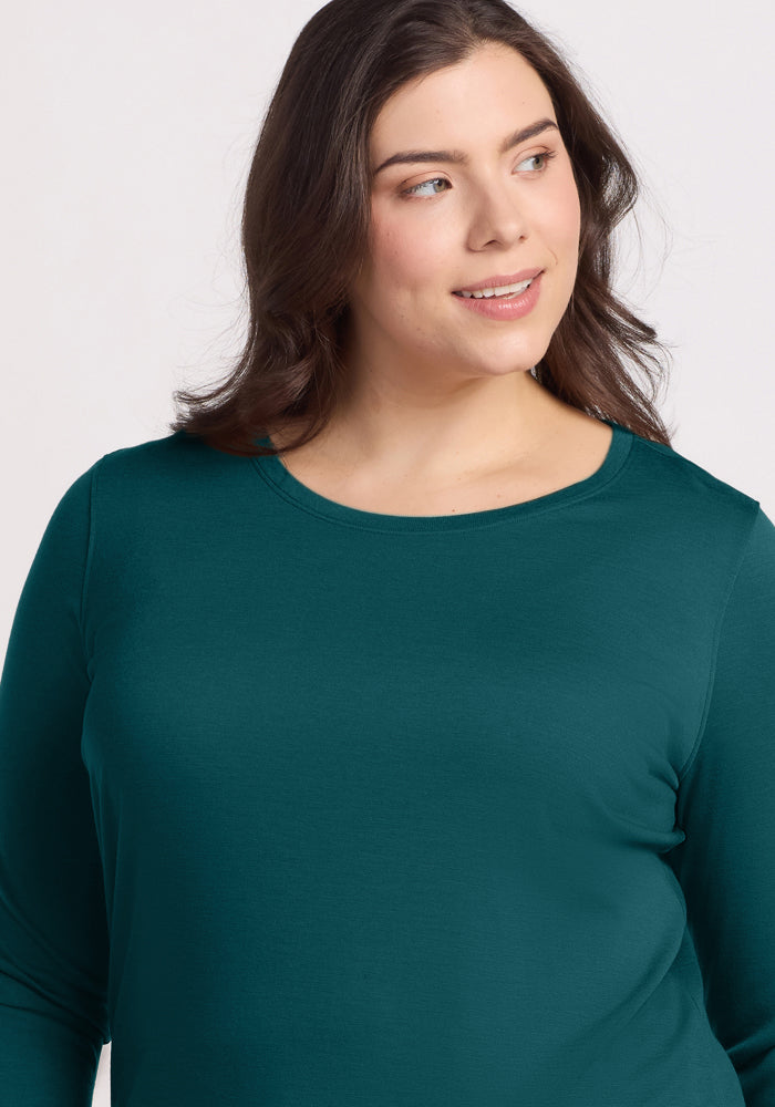 A woman with long brown hair wears the Woolx Jenny 3/4 Sleeve Crew Neck in Riverbank Green, smiling softly and looking slightly to her left against a plain light background.