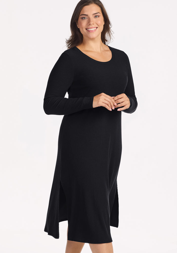 Woman smiling in the Woolx Caroline Ribbed Twirl Dress - Black, knee-length, wrinkle-resistant, on white background.