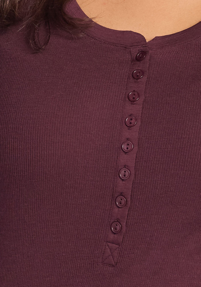 Close-up of a person wearing the Woolx Reese Ribbed Henley in Chocolate Fig, a women's winter top featuring a ribbed texture and buttoned front. Only the upper chest and neckline are visible.