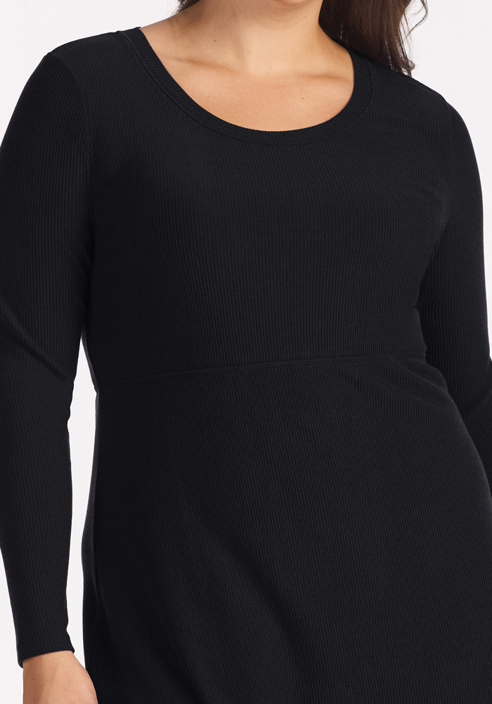 Woman in Woolx Caroline Ribbed Twirl Dress, black, long-sleeve, shown shoulder to mid-thigh on white background.