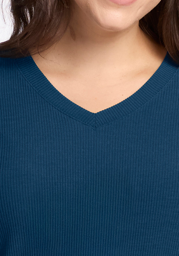 A close-up of a person wearing the Woolx Evie Ribbed Tunic in Majolica Blue, showing the lower half of their face, neck, and upper chest with long dark hair—an ideal choice for temperature regulating comfort.