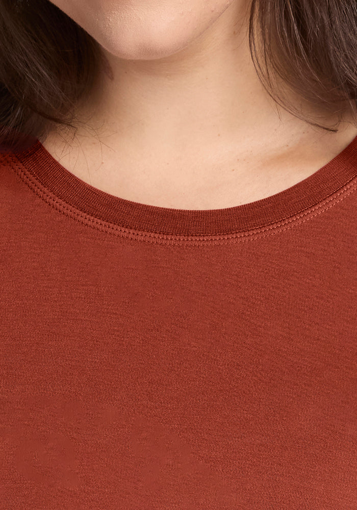 Close-up of a person wearing the Woolx Blair Tunic in Maple Leaf, highlighting the neckline and part of their chin and neck, with shoulder-length brown hair partially visible.