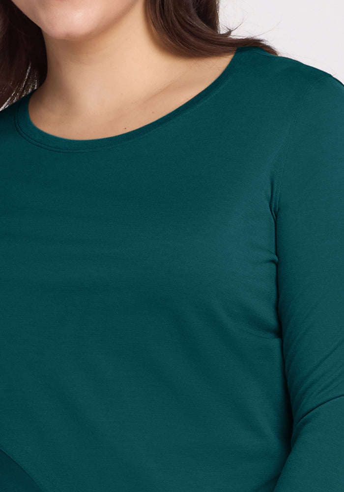 A close-up of a person with long brown hair wearing the Woolx Jenny 3/4 Sleeve Crew Neck in Riverbank Green, highlighting the shirt's upper chest, shoulder, neck, and part of the face.
