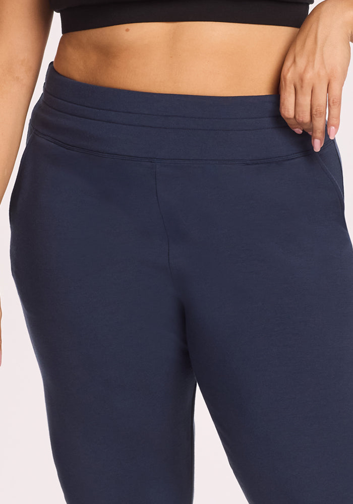 Someone wearing a black crop top and Woolx Willa Joggers in Deep Navy, with one hand on their hip, poses against a light background.